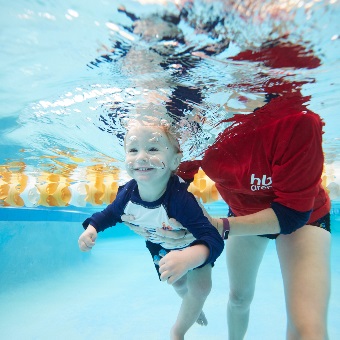 Underwater view of swim instructor teaching pre-school aged swimmer