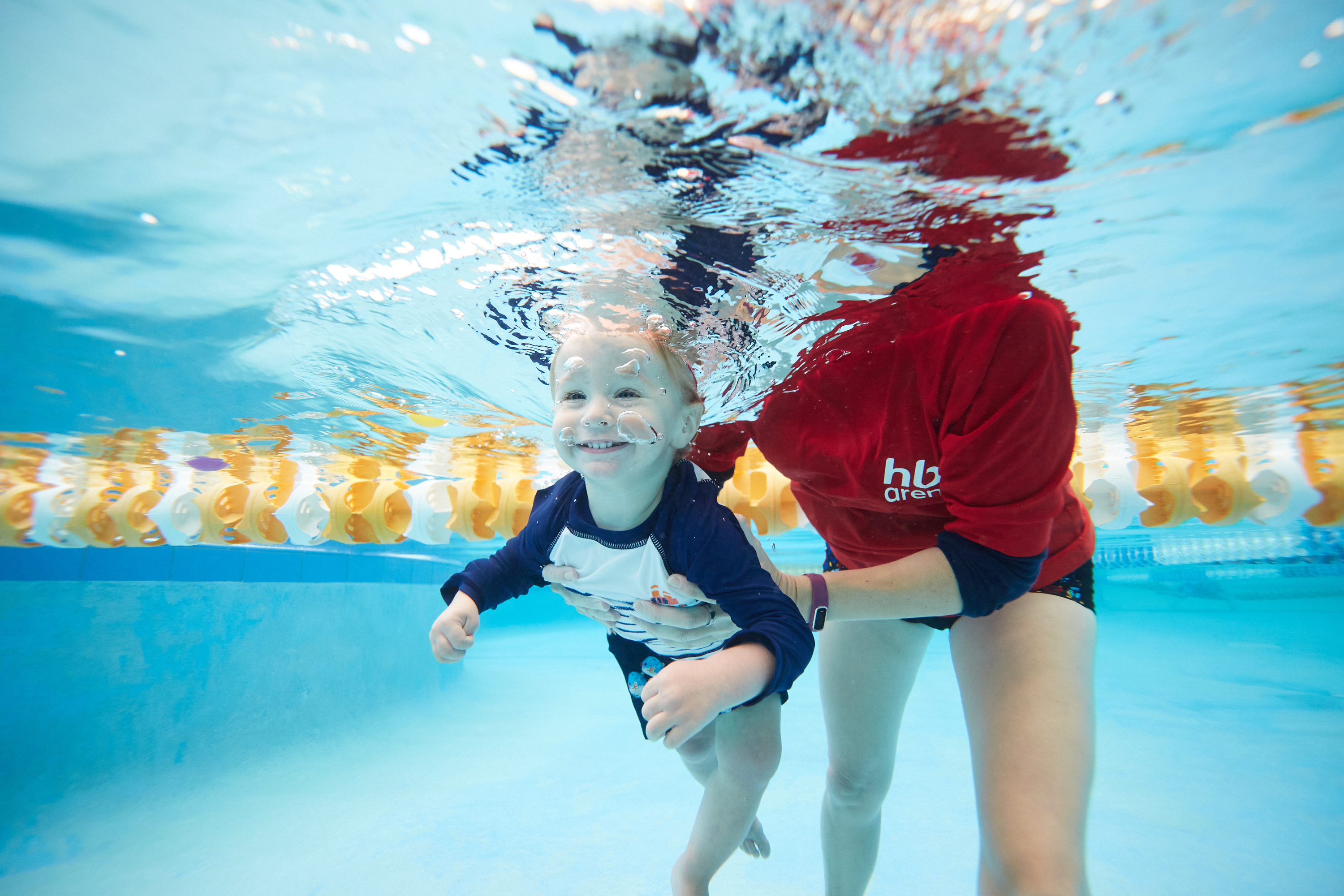 Underwater view of swim instructor teaching pre-school aged swimmer