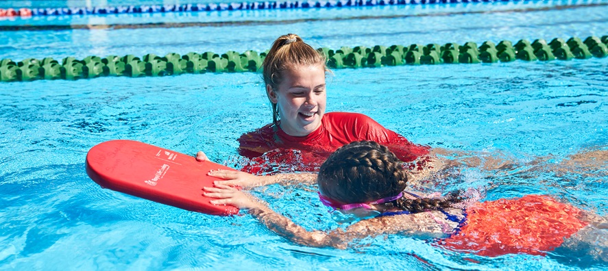 kid learning to swim by instructor