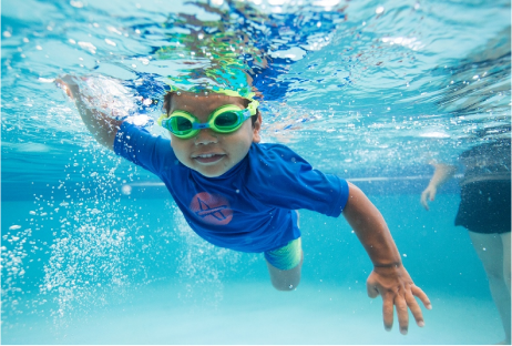 Underwater view of happy young boy swimming freestyle