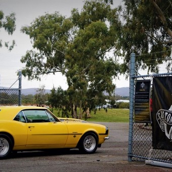 A photo of a car next to a sign advertising the custom cars and coffee event held at the Speeddome in Middle Swan, Perth