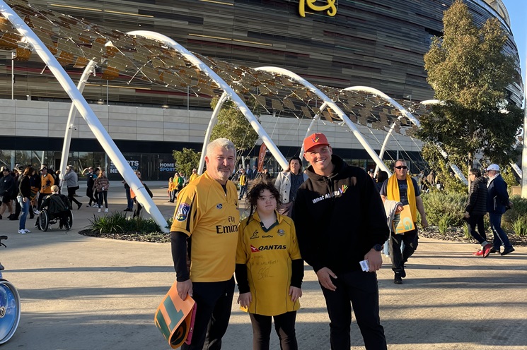 A photo of three people posing for a photo outside of Optus Stadium