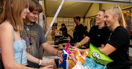 A photo of two cashiers selling food to two patrons