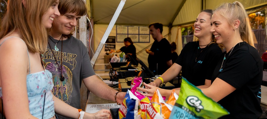 A photo of two cashiers selling food to two patrons